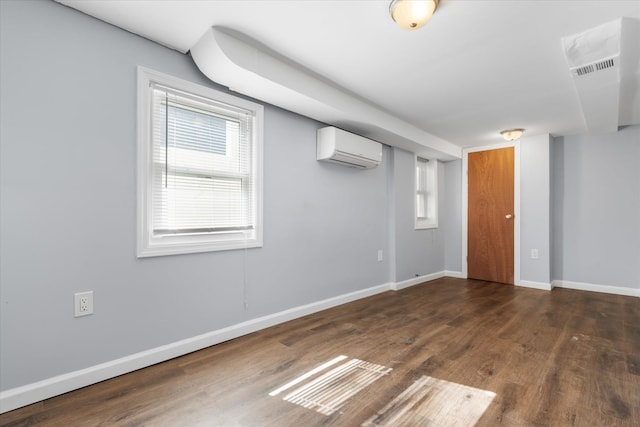 empty room with plenty of natural light, wood finished floors, baseboards, and a wall mounted AC