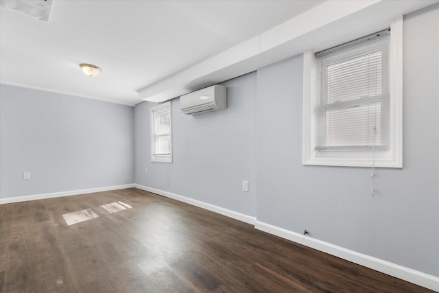 spare room with a wall mounted air conditioner, baseboards, and wood finished floors