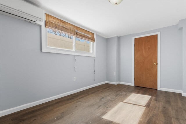 unfurnished room with baseboards, wood finished floors, and a wall mounted AC