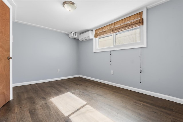 spare room featuring baseboards, an AC wall unit, and wood finished floors