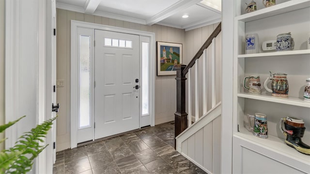 foyer entrance with beamed ceiling, ornamental molding, and wooden walls