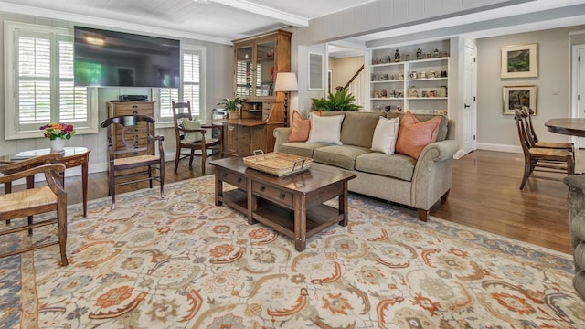 living room featuring beamed ceiling, crown molding, and light hardwood / wood-style floors