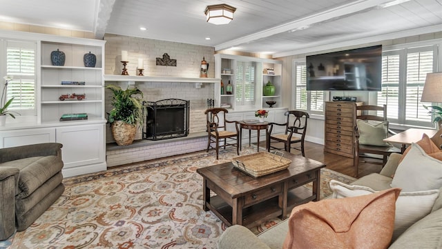 living room featuring beamed ceiling, a brick fireplace, and light hardwood / wood-style flooring