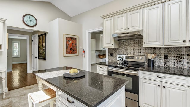 kitchen with lofted ceiling, tasteful backsplash, stainless steel range with electric stovetop, dark stone countertops, and white cabinets