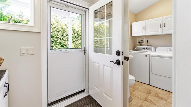 clothes washing area with light tile patterned flooring, cabinets, and washer and clothes dryer