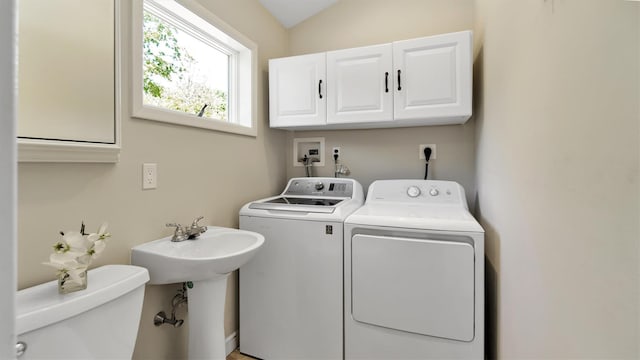 clothes washing area featuring cabinets and separate washer and dryer