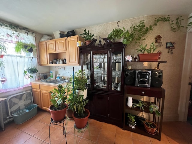 kitchen with light brown cabinets, a healthy amount of sunlight, a sink, and light tile patterned floors