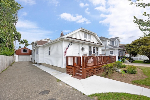 view of front of home with a garage, a wooden deck, and an outdoor structure