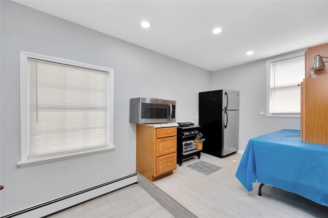 interior space featuring stainless steel appliances, baseboard heating, and light hardwood / wood-style floors