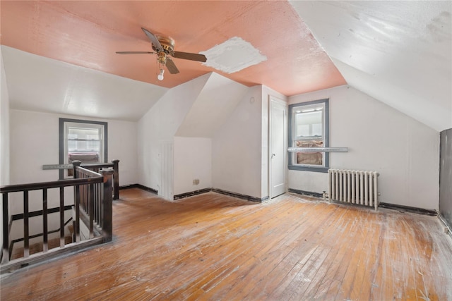 additional living space with lofted ceiling, radiator heating unit, and light hardwood / wood-style floors