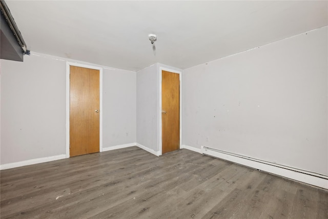 empty room with dark hardwood / wood-style flooring and baseboard heating