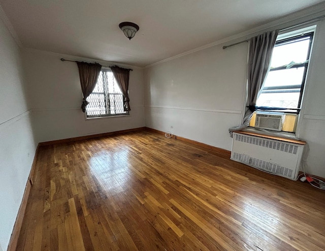 empty room featuring radiator, crown molding, and hardwood / wood-style floors