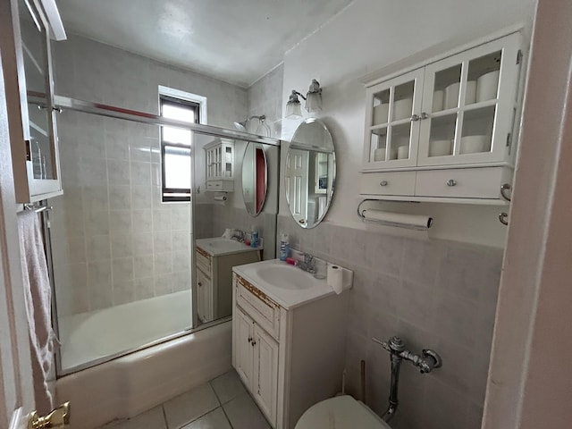 bathroom with tile walls, vanity, tile patterned floors, and shower / bath combination with glass door