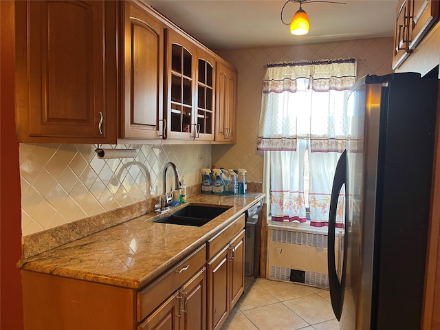 kitchen with radiator heating unit, sink, black dishwasher, fridge, and light stone countertops