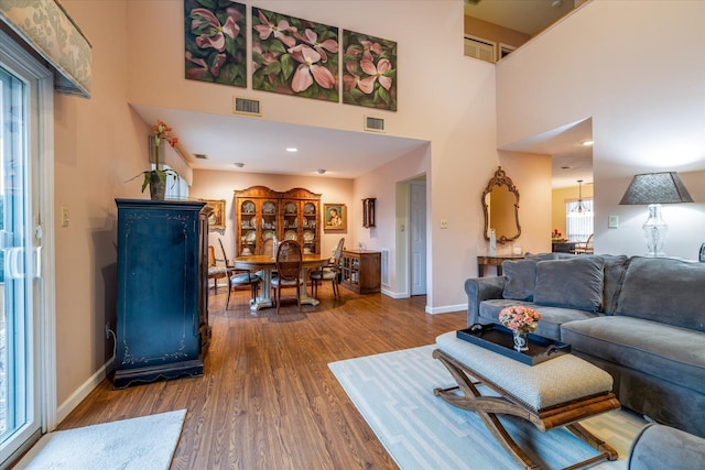 living room featuring visible vents, wood finished floors, and a towering ceiling