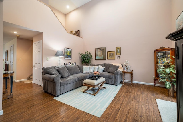 living area with baseboards, a high ceiling, and dark wood-style floors