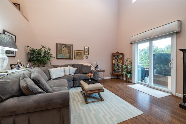living room with baseboards, a high ceiling, and wood finished floors