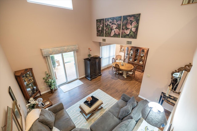 living area featuring baseboards, visible vents, wood finished floors, and a towering ceiling