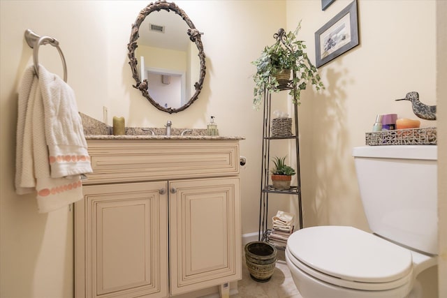 half bath featuring visible vents, baseboards, toilet, and vanity