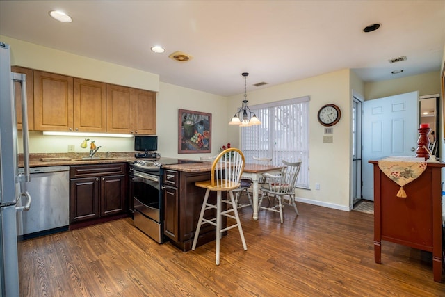 kitchen with light stone counters, a sink, dark wood finished floors, and appliances with stainless steel finishes