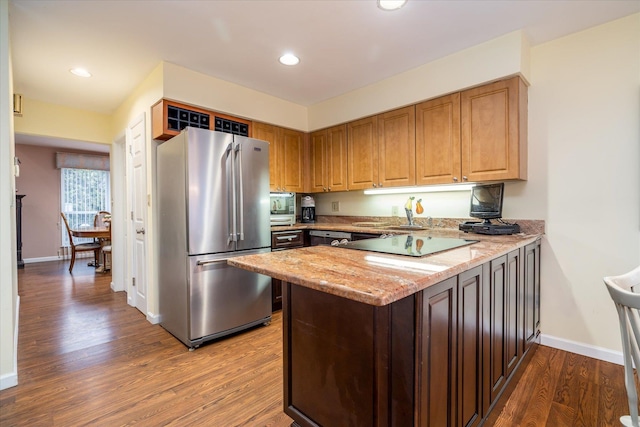 kitchen featuring freestanding refrigerator, a peninsula, baseboards, dark wood-type flooring, and light stone counters
