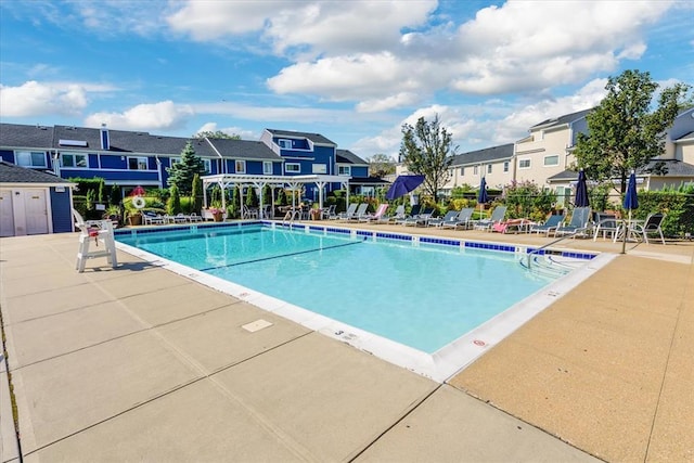 community pool with a patio, fence, and a residential view