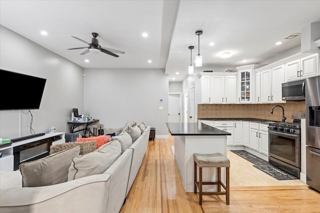 kitchen featuring appliances with stainless steel finishes, hanging light fixtures, a kitchen breakfast bar, tasteful backsplash, and white cabinets