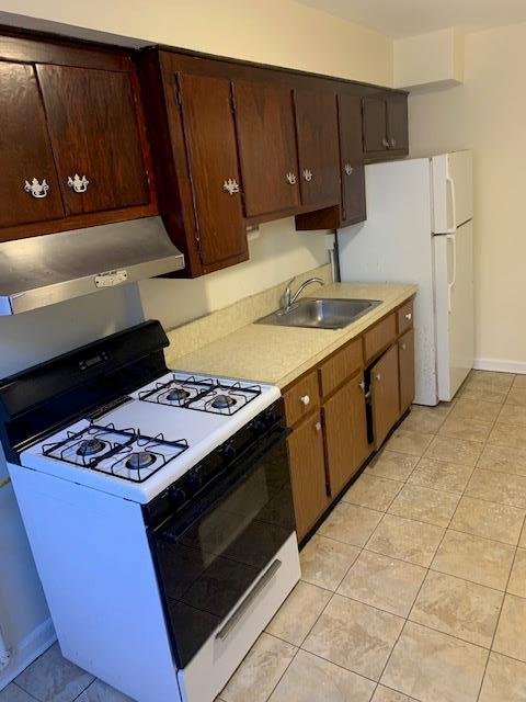 kitchen featuring white appliances, sink, and light tile patterned floors