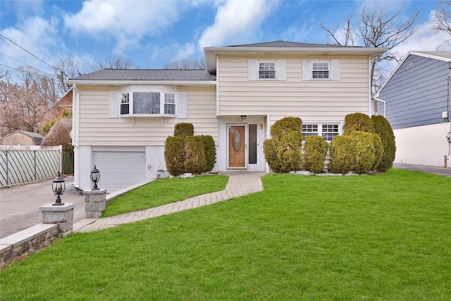 split level home featuring an attached garage, driveway, fence, and a front lawn