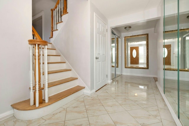 foyer entrance featuring stairs, marble finish floor, and baseboards