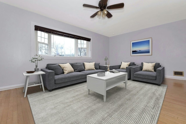 living area featuring light wood finished floors, a ceiling fan, visible vents, and baseboards