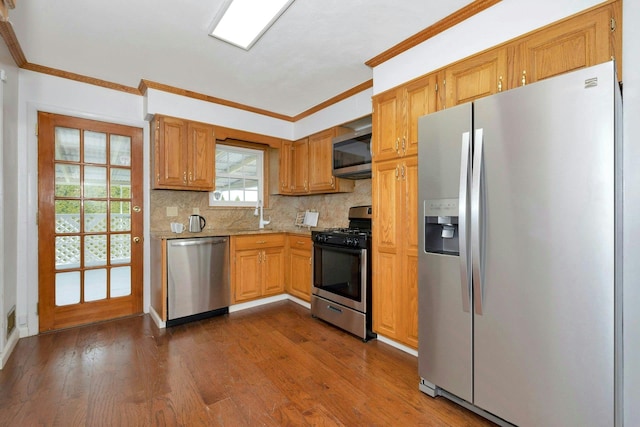 kitchen featuring appliances with stainless steel finishes, dark wood-type flooring, crown molding, and decorative backsplash