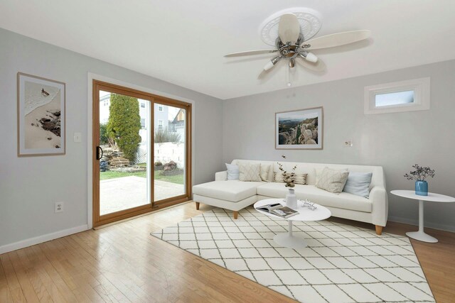 living room featuring baseboards, a ceiling fan, and light wood-style floors