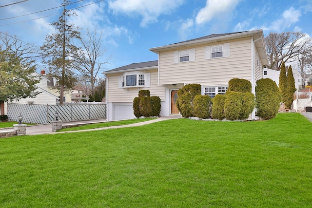 view of front facade with a garage, a front lawn, and fence