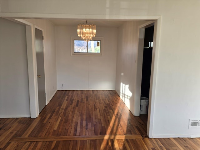 unfurnished dining area featuring dark wood-type flooring and a notable chandelier