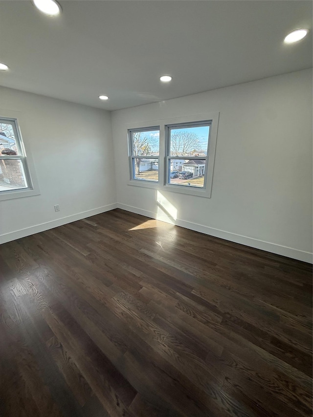 empty room with dark hardwood / wood-style floors and a healthy amount of sunlight