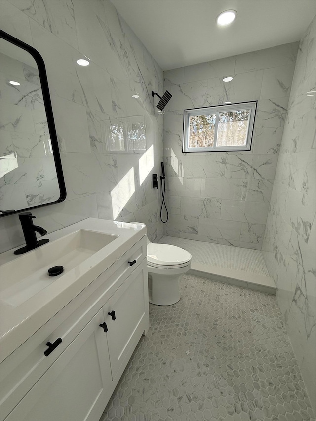 bathroom featuring tiled shower, vanity, toilet, and tile walls