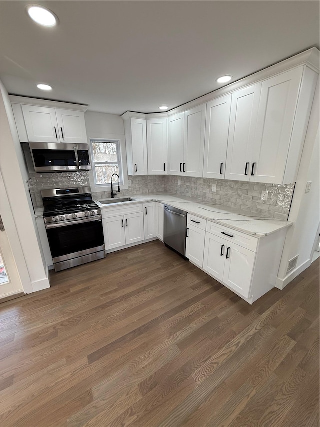 kitchen with backsplash, stainless steel appliances, sink, and white cabinets