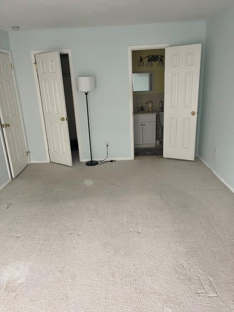 unfurnished bedroom with ensuite bathroom and light carpet