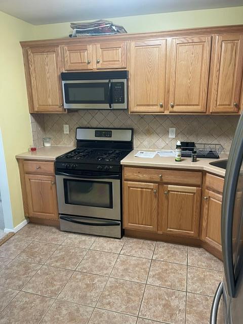 kitchen with backsplash, appliances with stainless steel finishes, and light tile patterned floors