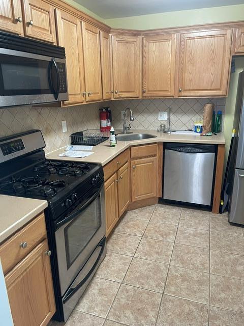 kitchen featuring tasteful backsplash, sink, light tile patterned floors, and appliances with stainless steel finishes