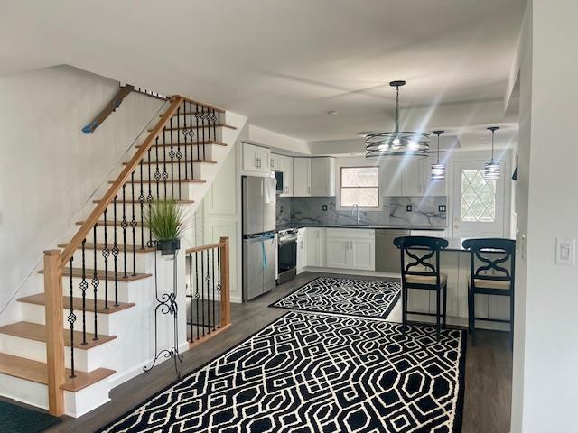 kitchen with stainless steel appliances, backsplash, a sink, and white cabinetry