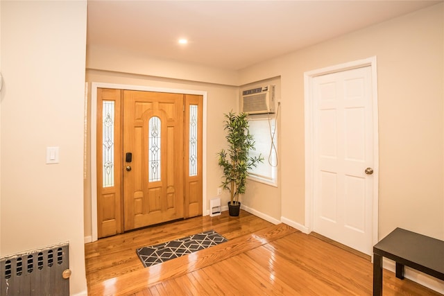 foyer with baseboards, a wall unit AC, hardwood / wood-style flooring, and radiator