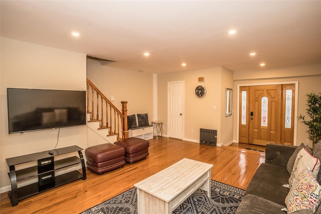 living area with radiator heating unit, stairs, wood finished floors, and recessed lighting