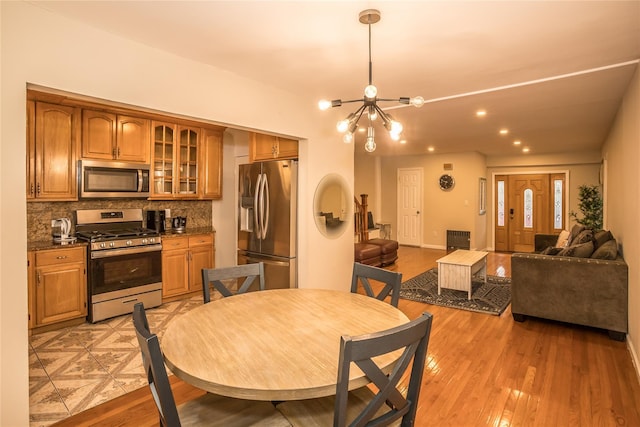 dining room featuring a chandelier, light wood-type flooring, radiator heating unit, and recessed lighting