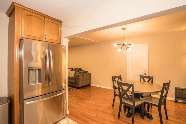 dining space with an inviting chandelier, light wood-style flooring, and baseboards