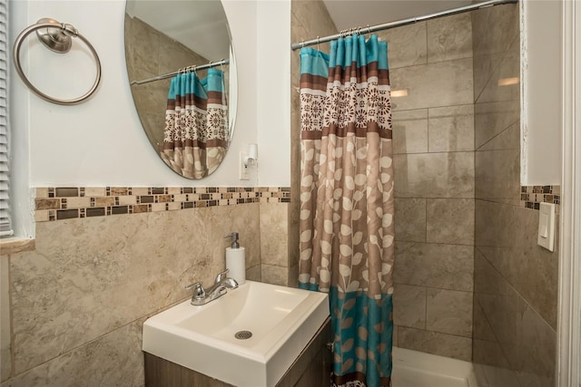 full bath with tiled shower, vanity, and tile walls