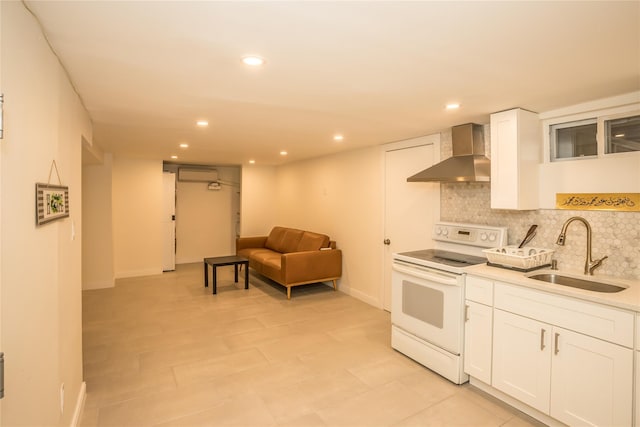 kitchen featuring tasteful backsplash, white range with electric cooktop, white cabinets, wall chimney range hood, and a sink