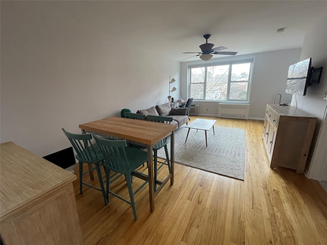 dining area featuring light hardwood / wood-style flooring, radiator heating unit, and ceiling fan