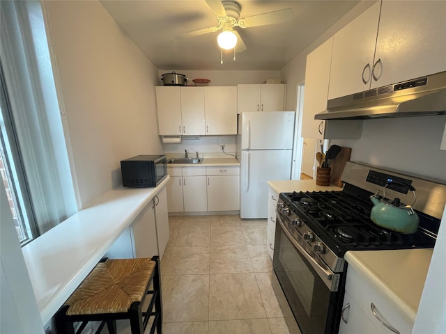 kitchen featuring sink, white cabinets, white fridge, light tile patterned floors, and stainless steel gas range